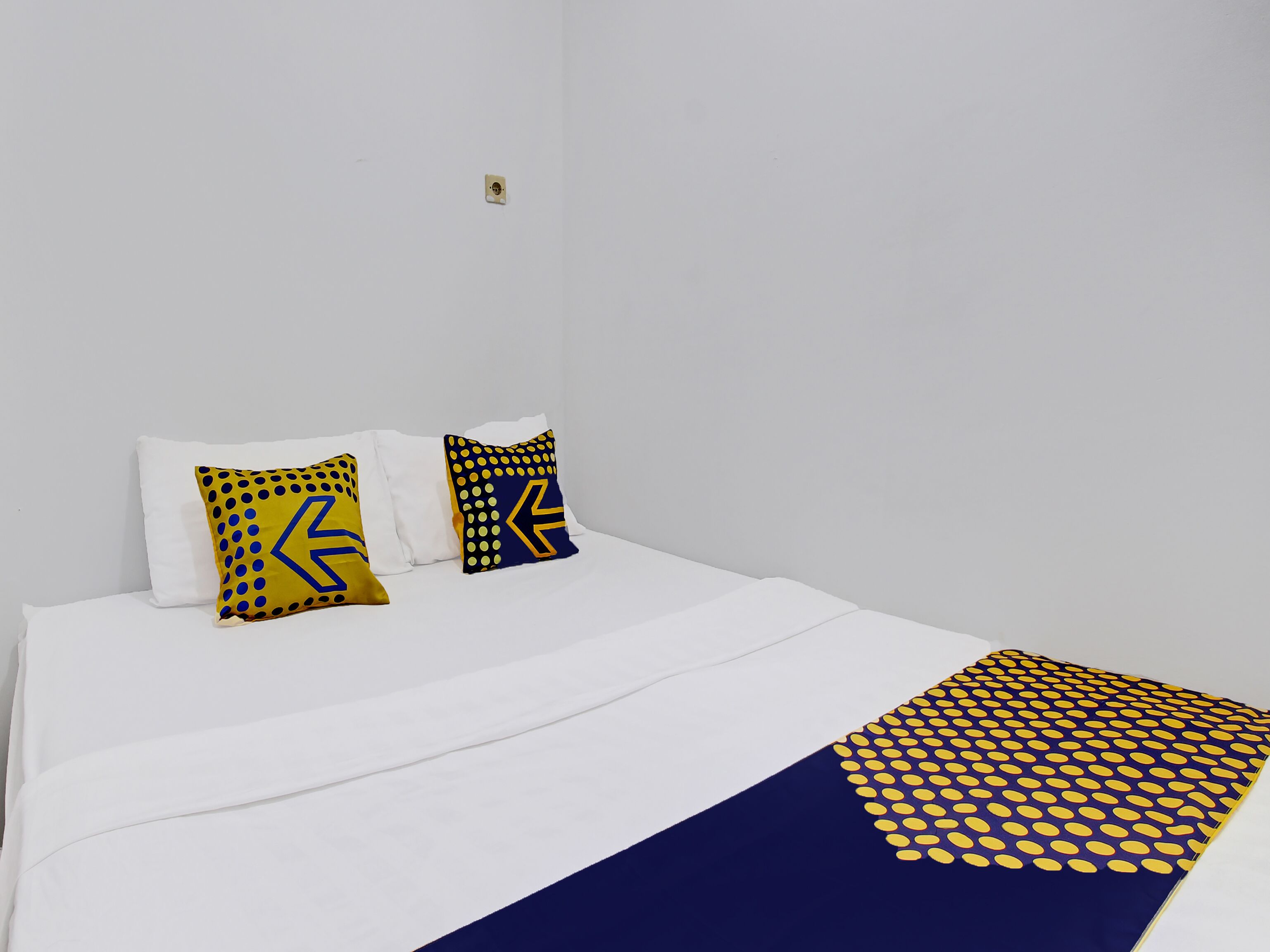 A bed with white bedding and two decorative pillows with geometric patterns.