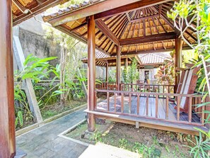 A wooden gazebo with a tiled roof, surrounded by lush greenery and a stone wall. - Hotel O Orchid Guest House (Yogyakarta)