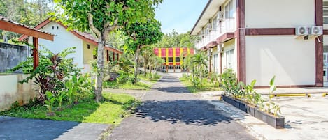 Un camino que lleva a un edificio con varios balcones y unidades de aire acondicionado.
