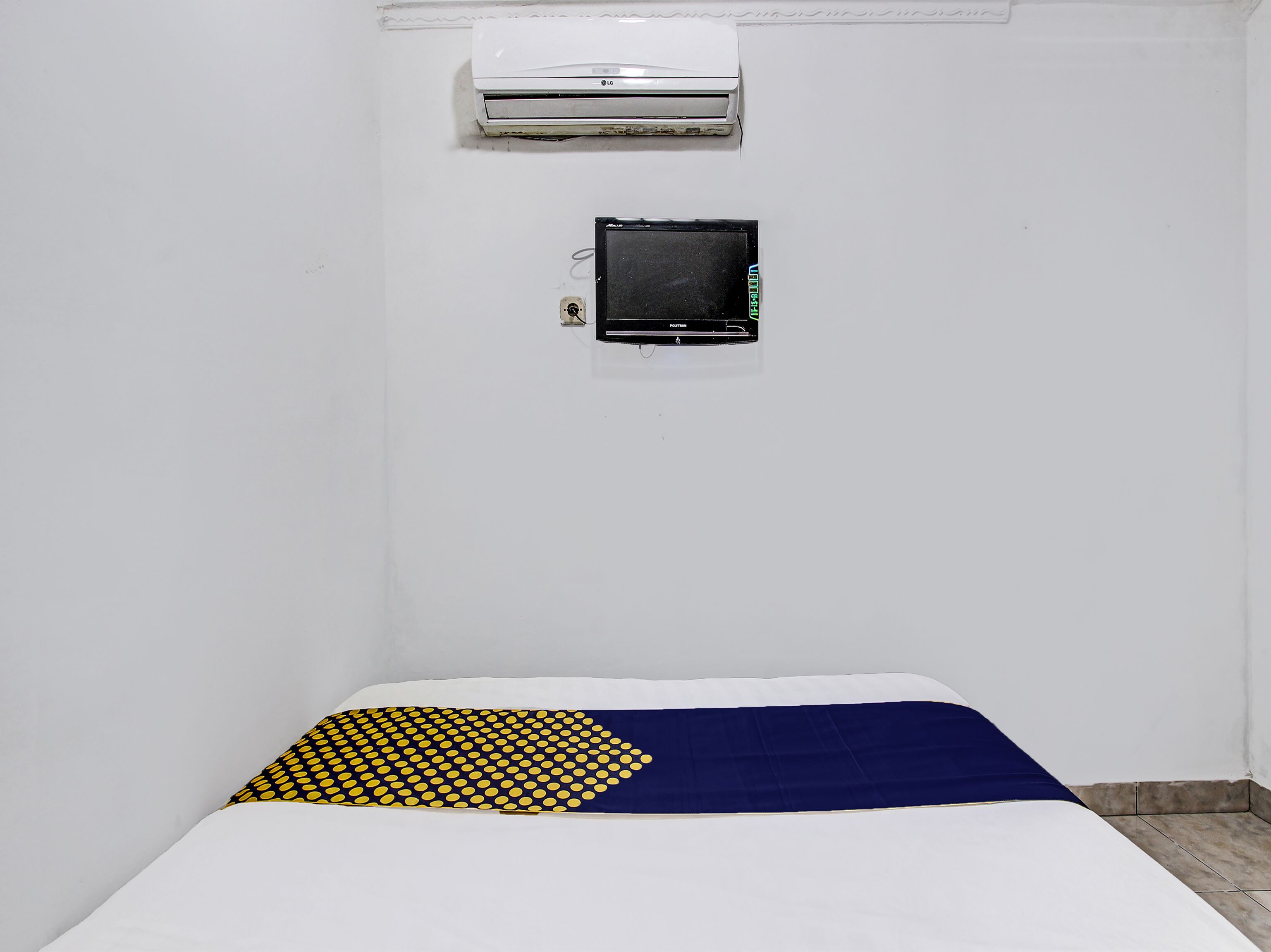 A room with a bed, a wall-mounted air conditioner, and a television.