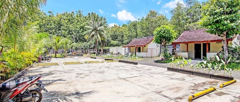 A spacious outdoor area with a paved surface, yellow bollards, and a parked motorcycle.