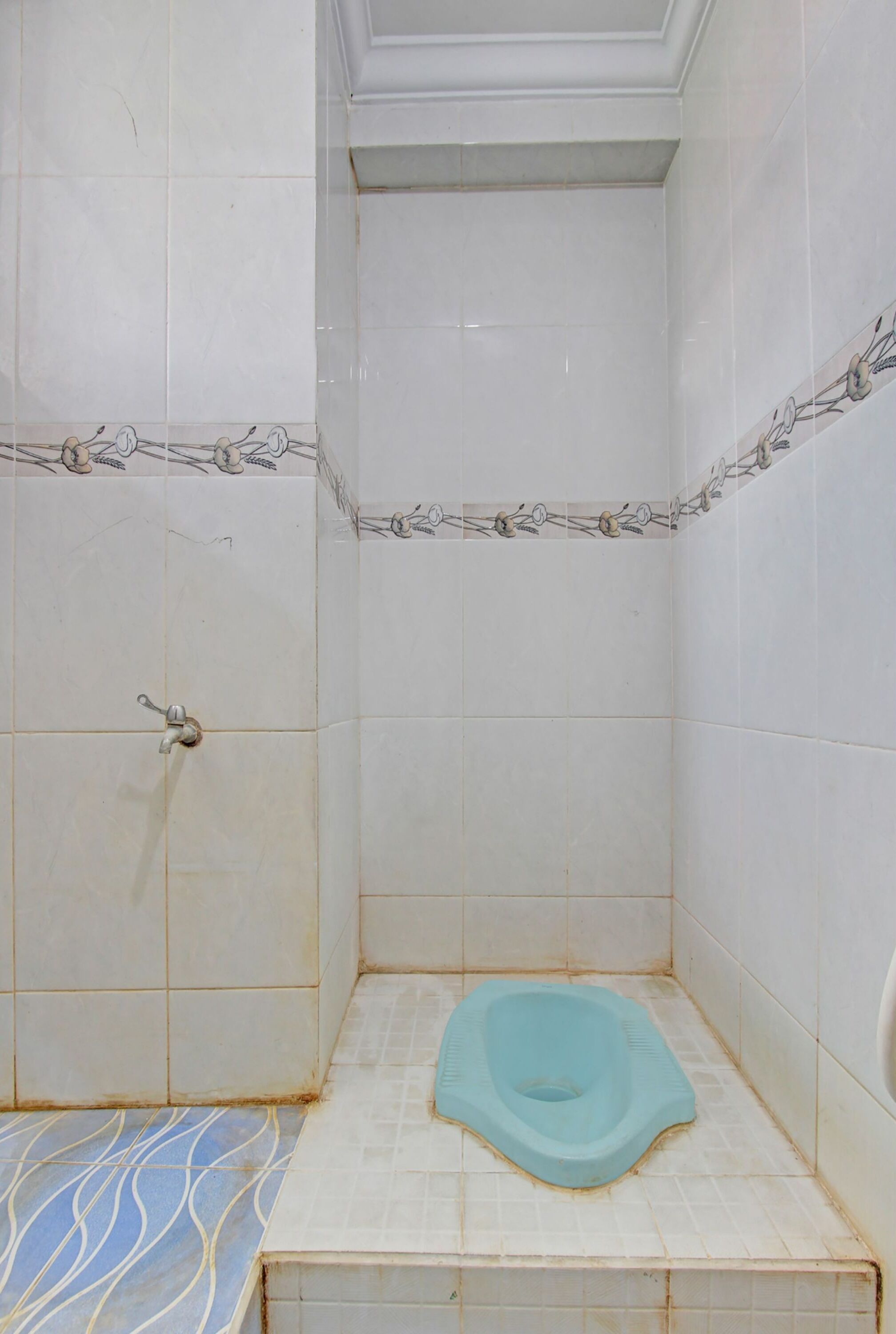 A small, tiled bathroom with a toilet, a shower area, and a door.