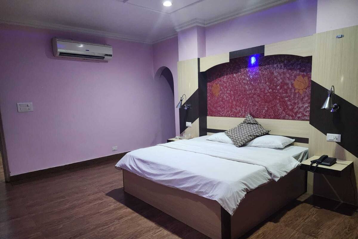 Quarto com uma cama grande, mesa de cabeceira, abajur e ar condicionado.