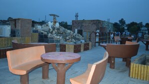 An outdoor seating area with terracotta furniture and a statue. - Hotel Meridian Palace (Jammu)