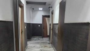 A hallway with dark tiled walls, a marble floor, and a ceiling with recessed lighting. - Hotel Meridian Palace (Jammu)