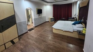 A hotel room with a bed, a desk, a chair, a TV, and a wardrobe. - Hotel Meridian Palace (Jammu)