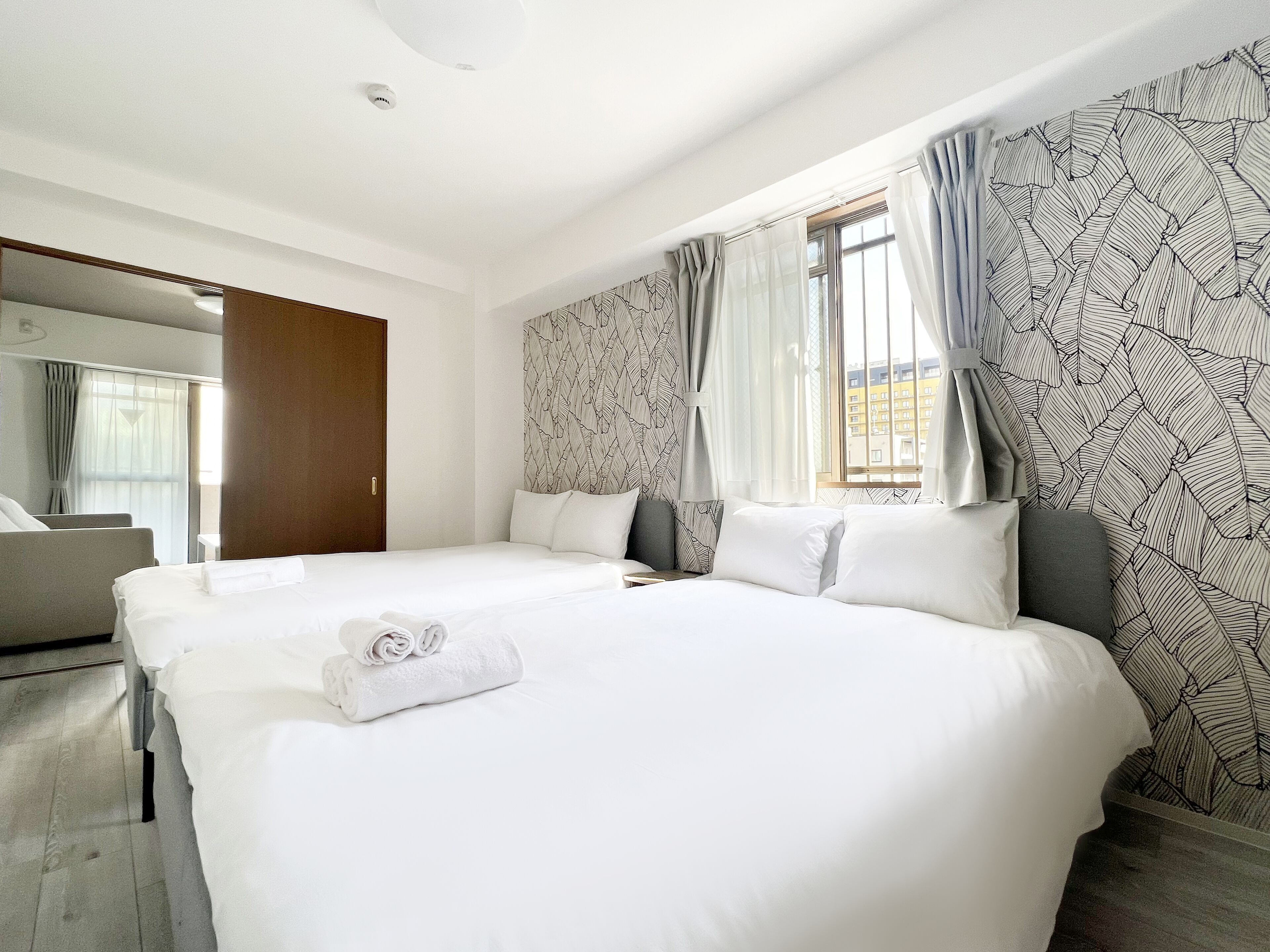 Habitació d'hotel amb un llit gran, una taula de treball, una cadira i una finestra amb cortines.