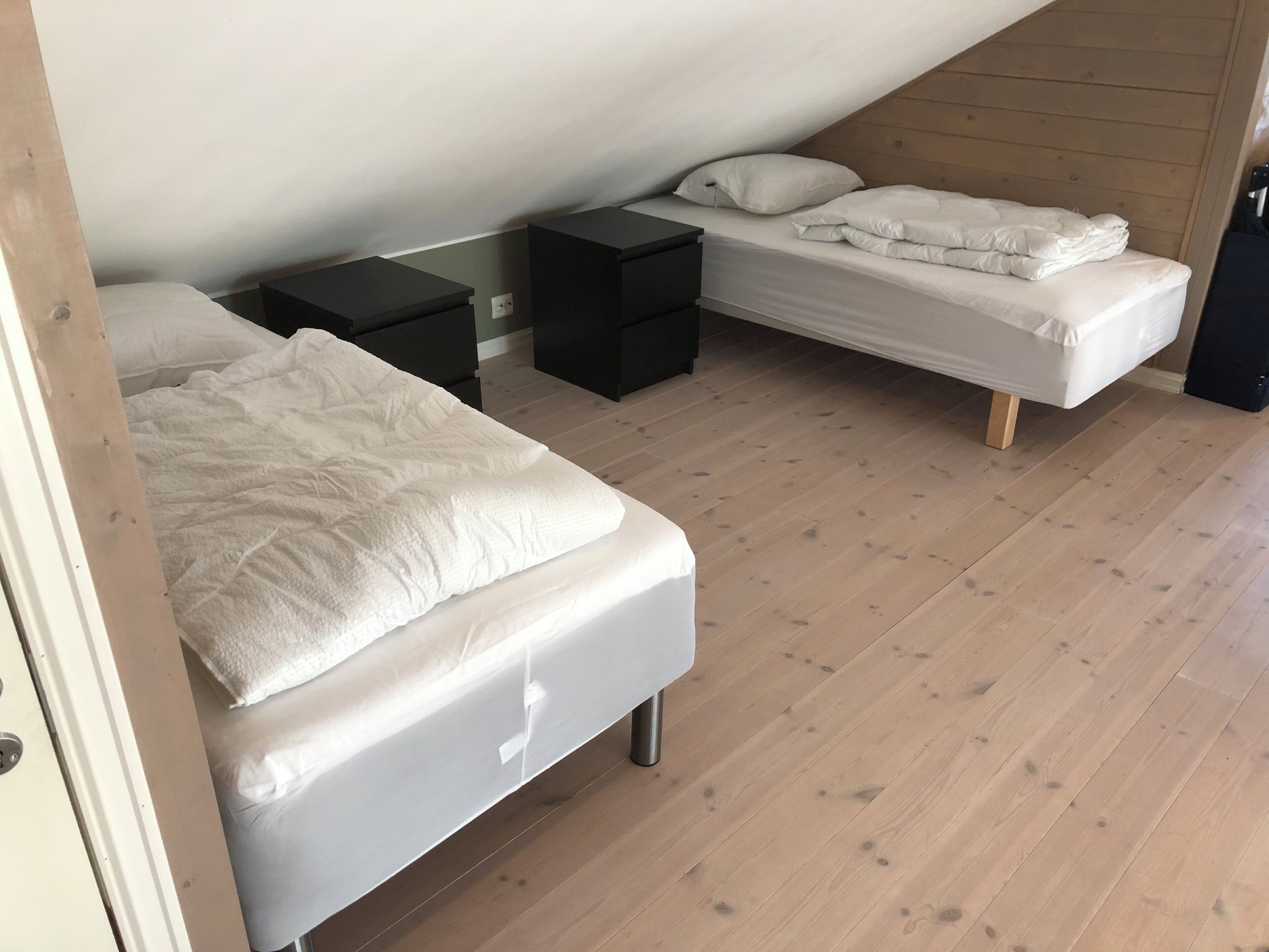 Ein Schlafzimmer mit zwei Betten, Holzboden und schrägen Decken.