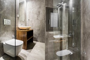 Enjoy a refreshing shower in the sleek shower with handheld showerhead and faucet, accompanied by a spacious vanity and large mirror.