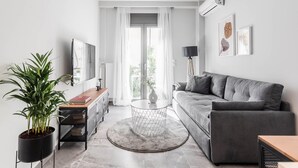 Una sala moderna con un sofá gris, una mesa de centro redonda y una planta en maceta.