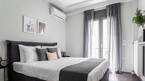 Un dormitorio moderno con una cama grande, cortinas grises y una planta en maceta.