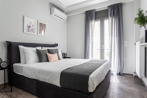 Relax in a spacious room with a large bed, wall-mounted air conditioning, and a side table with a clock.