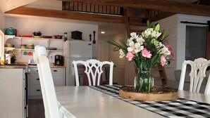 A dining area with a white table and chairs, a checkered table runner, and a vase of flowers. - Charming 3-bedroom house with WiFi, AC near Acadia National Park! (Otis)