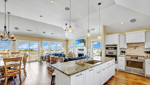Una cocina amplia con una isla grande, muebles de cocina blancos y electrodomésticos modernos.