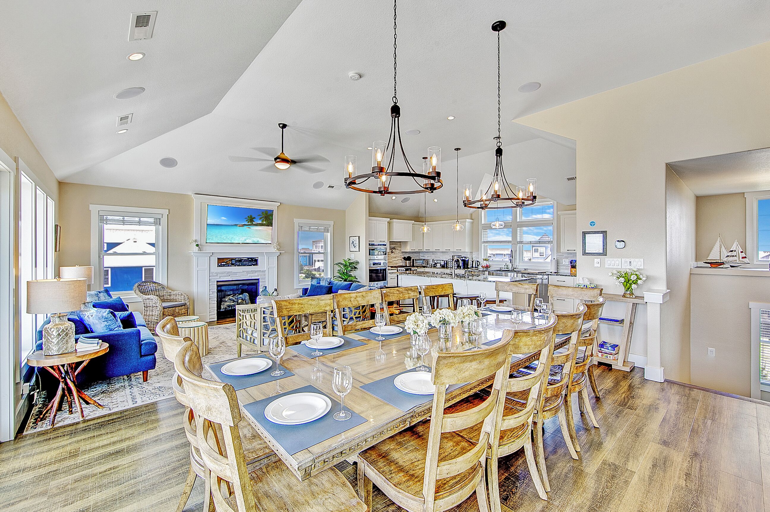 A spacious living room with a fireplace, a dining area set for six, and a kitchen with a large island.