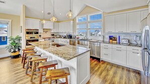Una cocina amplia con una isla grande, armarios blancos y un diseño moderno.