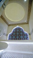 A view of a room with a patterned ceiling, a decorative arch, and a patterned window.