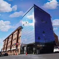 A hotel with a modern glass facade and a traditional brick building adjacent to it.