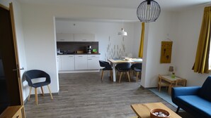 Een moderne woonkamer met een bank, een salontafel en een eethoek met stoelen en een tafel.