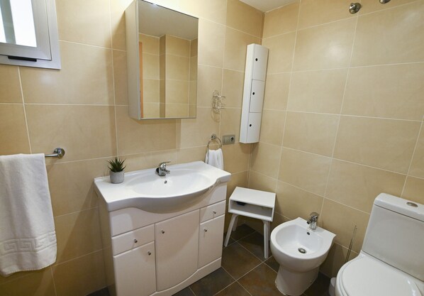 A bathroom with a sink, mirror, cabinet, bidet, and toilet.