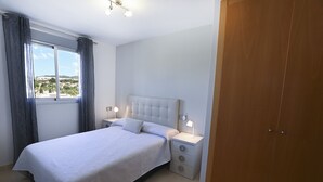 A bedroom with a bed, bedside tables, a wardrobe, and a window with curtains. - A104 COSTA CALPE 3º-7 (Calpe)