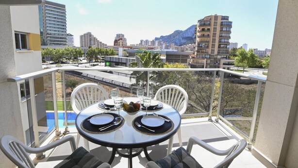 A balcony with a table set for two, overlooking a cityscape with buildings and a mountain. - A104 COSTA CALPE 3º-7 (Calpe)