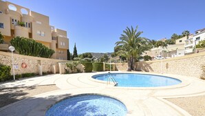 Una piscina de diseño circular, rodeada por un muro de piedra y palmeras.