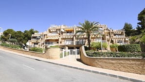 Un edificio residencial de varios pisos con balcones, antenas parabólicas y una entrada protegida por una reja.