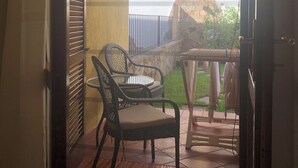 A room with a sliding door leading to an outdoor area. Inside, there is a black wicker chair and a small round table. - Comfortable and cozy Villasimius apartment 5 minutes from the center  (villasimius)