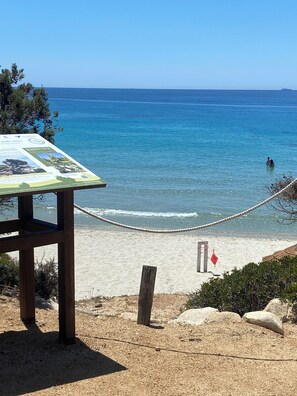 A beach with a wooden information board, a rope barrier, and a clear view of the sea. - Comfortable and cozy apartment in Villasimius, 5 minutes from downtown   (villasimius)