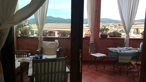 A balcony with a table set for dining, chairs, and a view of a mountainous landscape. - Comfortable and cozy Villasimius apartment 5 minutes from the center  (villasimius)