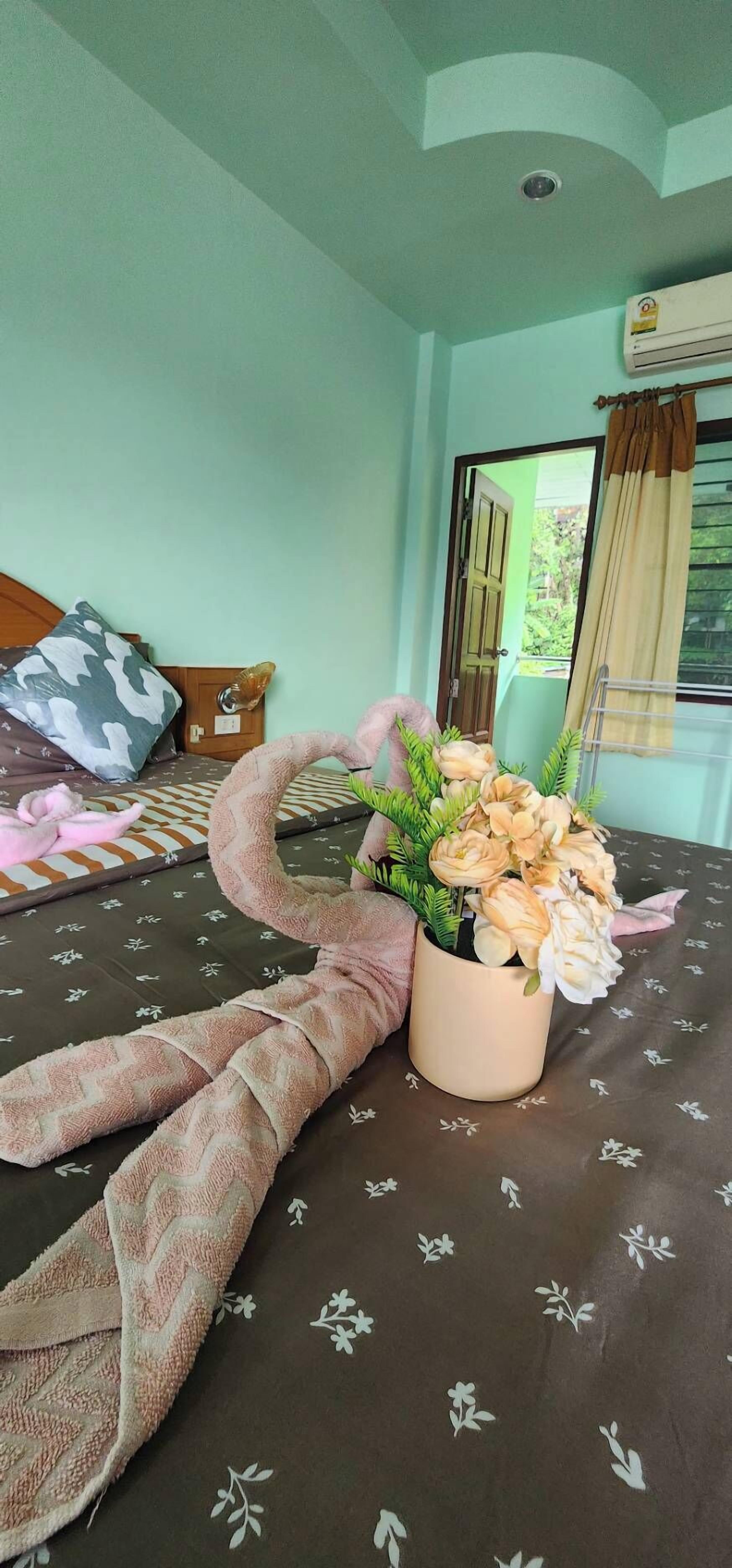 A bedroom with a bed, a potted plant, and a window with curtains.