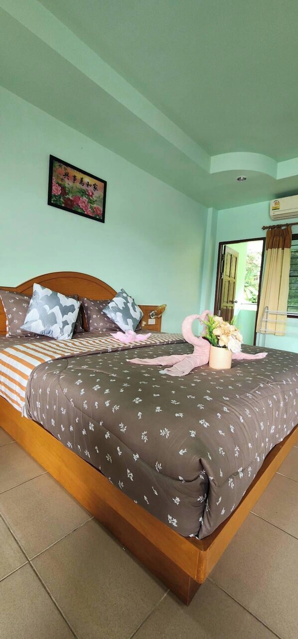Un dormitorio con cama, almohadas, un arreglo floral y un aire acondicionado de pared.