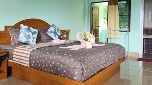 A neatly made bed with a floral-patterned bedspread, a wooden headboard, and a bedside table with a lamp. - PAILIN HILL (Patong)