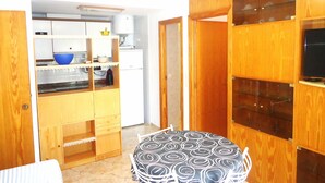 A compact kitchen with wooden cabinets, a small table, and a microwave. - El Peñon (Peñiscola)