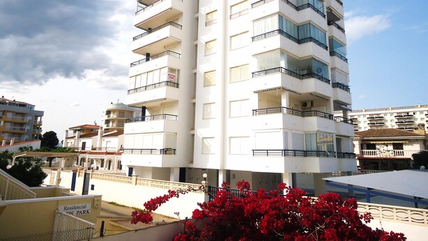 A multi-story residential building with balconies, a gated entrance, and a sign indicating it is a residential park. - El Peñon (Peñiscola)