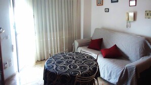 A room with a striped sofa, a patterned table, and a telephone on the wall. - El Peñon (Peñiscola)