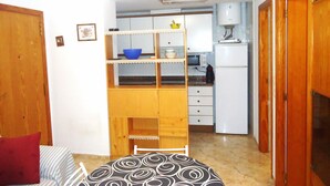 A compact kitchen with wooden cabinets, a microwave, and a refrigerator. - El Peñon (Peñiscola)