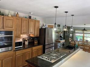 A modern kitchen with wooden cabinets, stainless steel appliances, and pendant lighting.