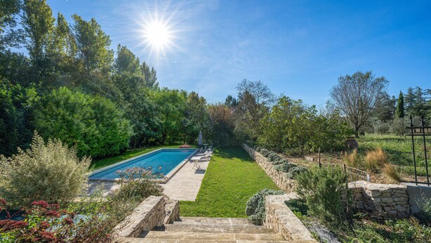 Un patio trasero con piscina, escalones de piedra y un muro de piedra.