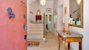 Un pasillo con suelo de mármol, un banco de madera, un espejo y una escalera que lleva a otra habitación.