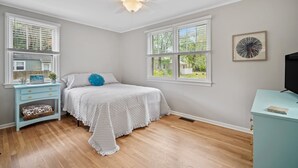 A bedroom with a bed, a nightstand, a dresser, and a ceiling fan.