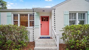 A house with a red door, light blue shutters, and a 'Hello' mat.