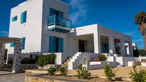 A modern white building with blue accents, including shutters and railings, featuring a staircase leading to a covered entrance. - Golden View Villa in Golden Beach With Private Swimming Pool (Paros)