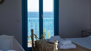 A room with a bed, a window with a view of the sea, and a small table. - Golden View Villa in Golden Beach With Private Swimming Pool (Paros)