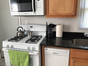 Uma cozinha equipada com micro-ondas, fogão e máquina de lavar louça.