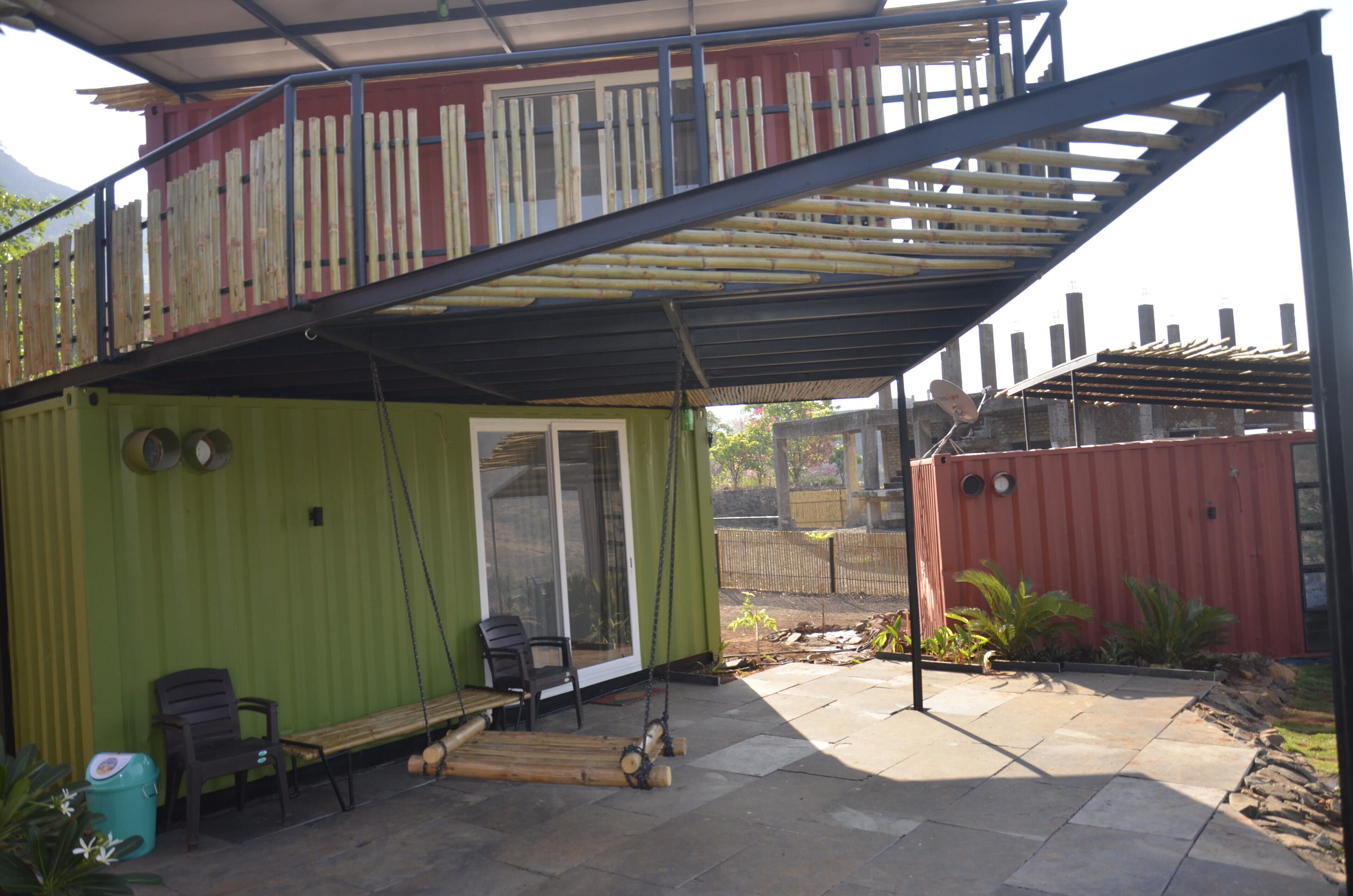 A covered patio area with a swing set, seating, and a sliding glass door leading to a green room.