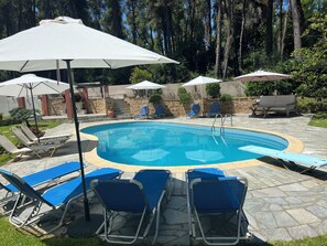 Relax by the pool surrounded by lush greenery and tall trees.