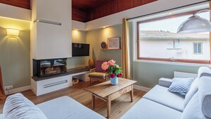 A modern living room with a fireplace, sofa, and a large window. - Maison Lamina - Welkeys (Anglet)