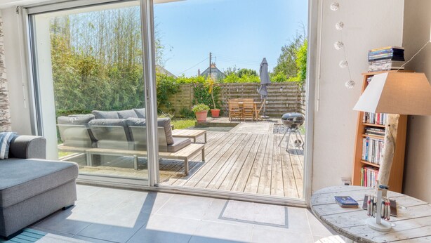 A modern living room with a sliding glass door leading to a wooden deck.